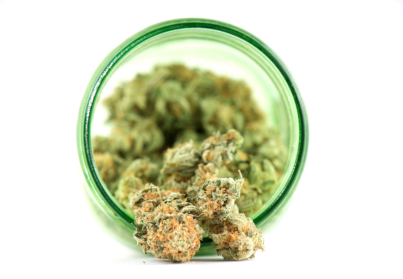 Cannabis flower spilling out of a green jar