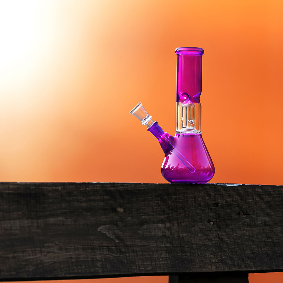 Pink bong on a table in front of an orange wall