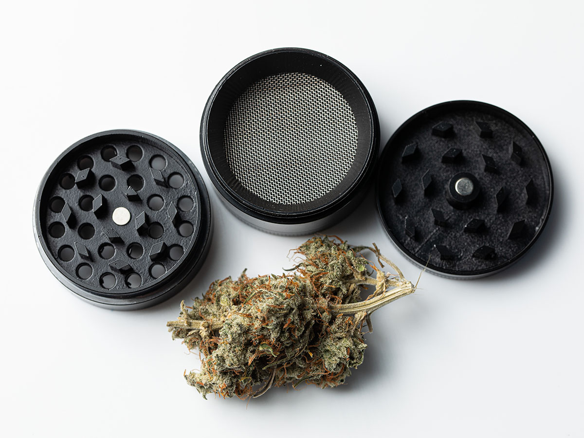 Three-piece grinder laying in pieces next to a flower bud