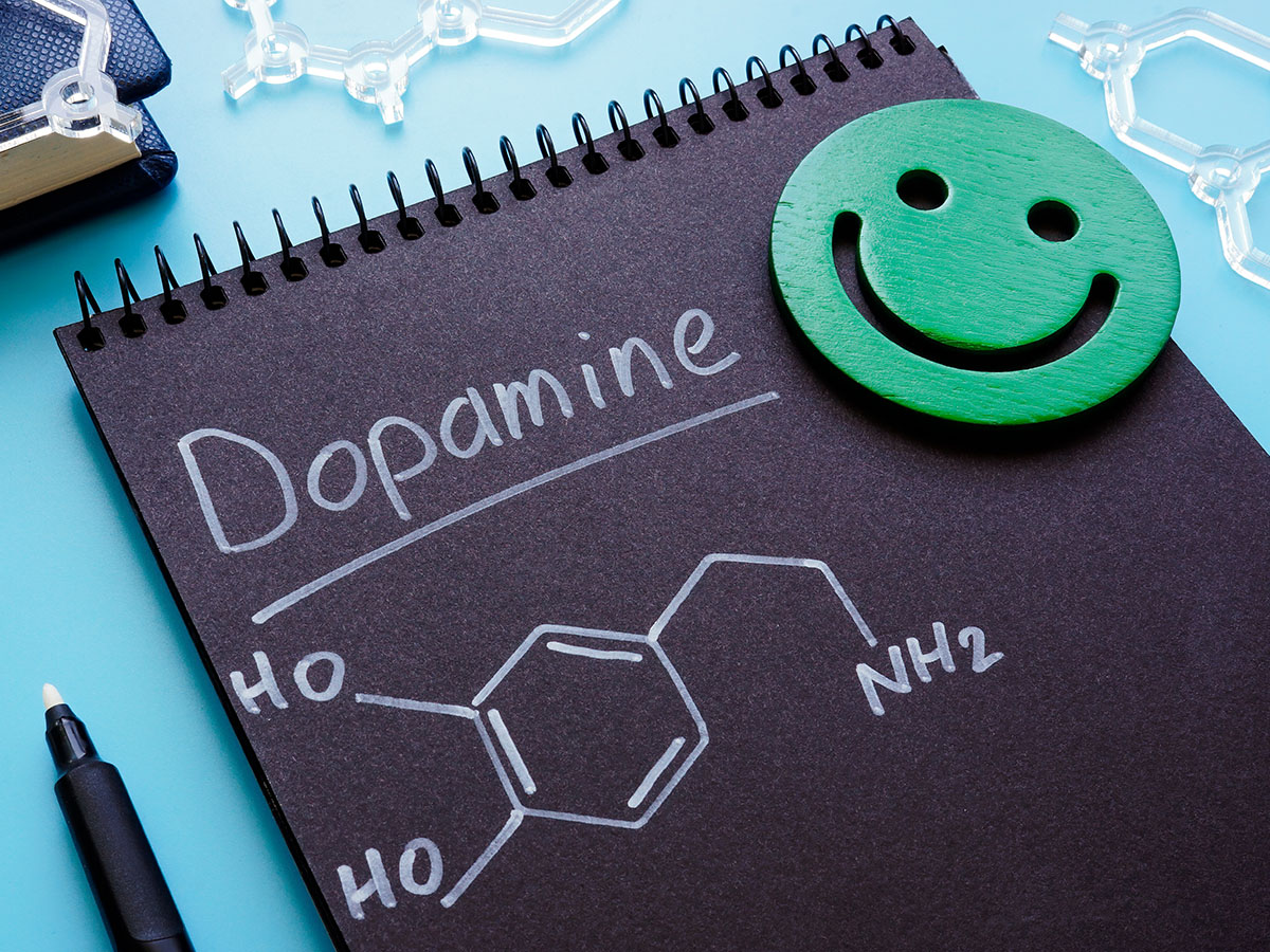 Black notebook paper with Dopamine written on it and the molecule drawing next to a green smiley face