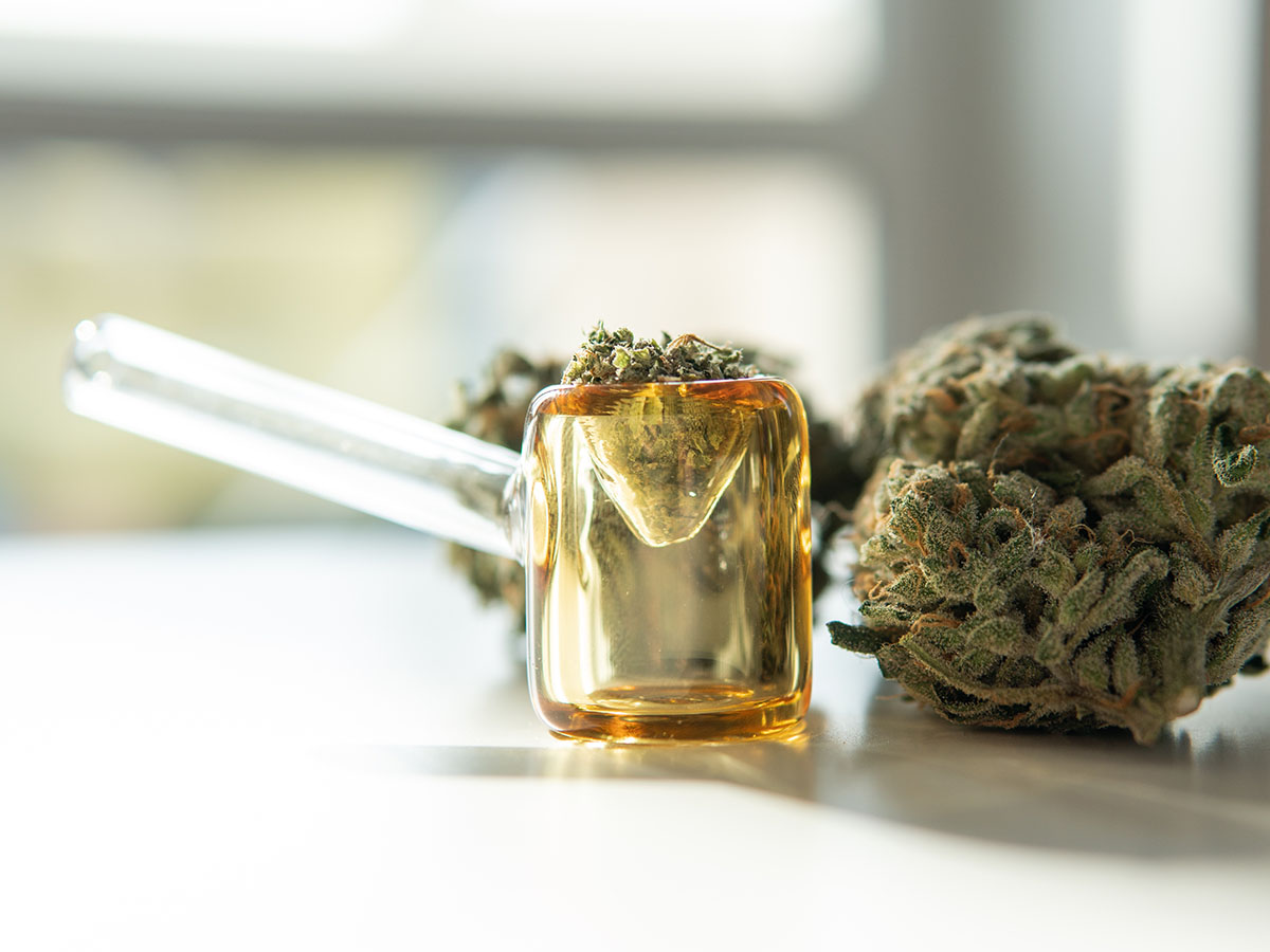 Glass marijuana pipe on a table with a bud of flower in it